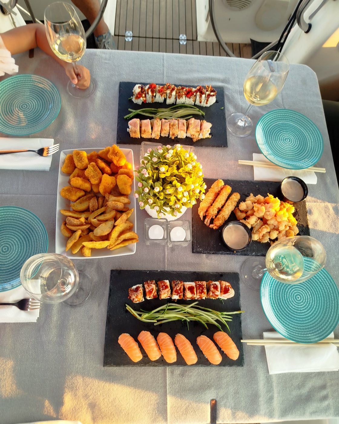 A table laid on deck at sunset, platters of food set out and wine poured