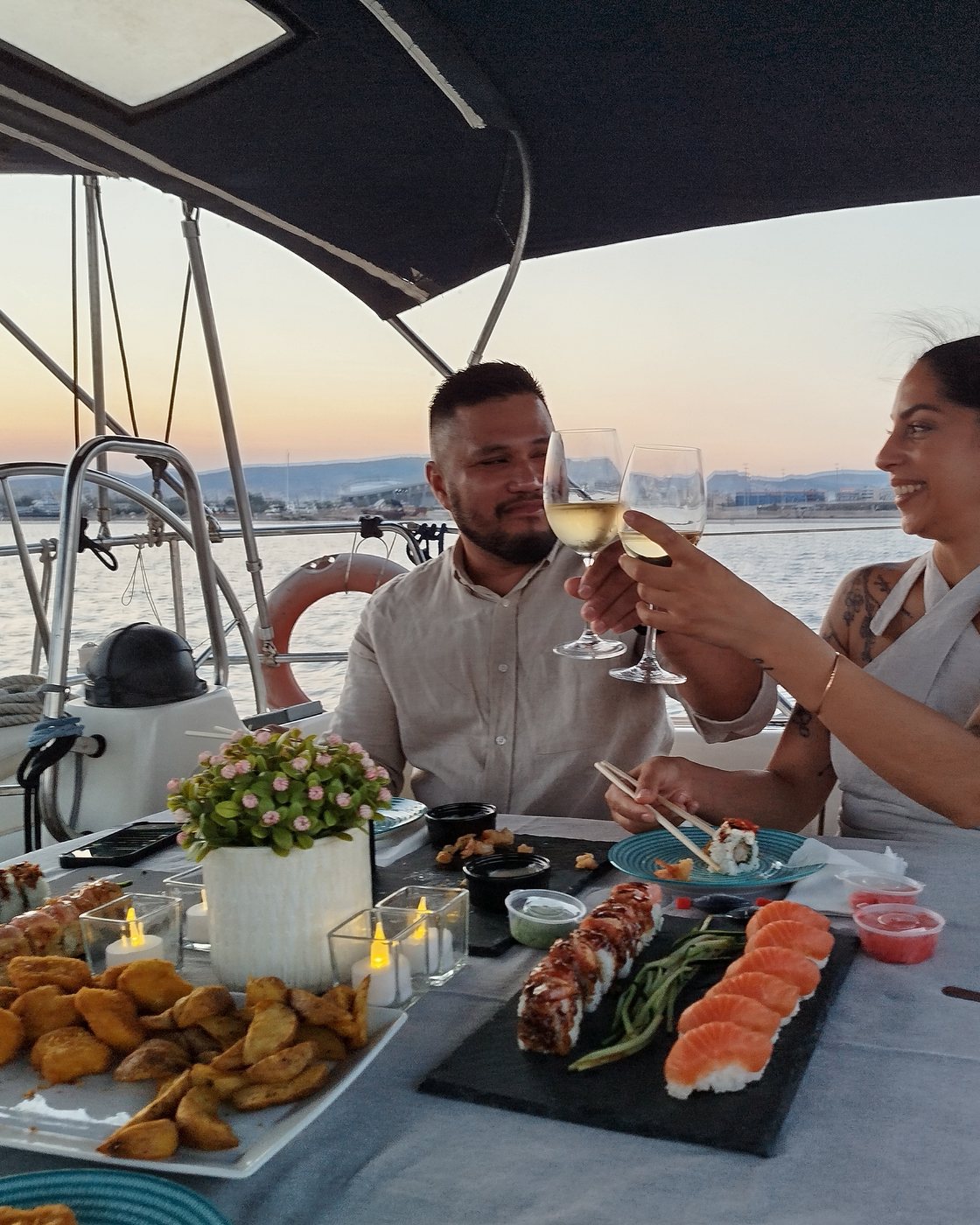The couple at the laid table, raising their glasses to each other as the sun goes down