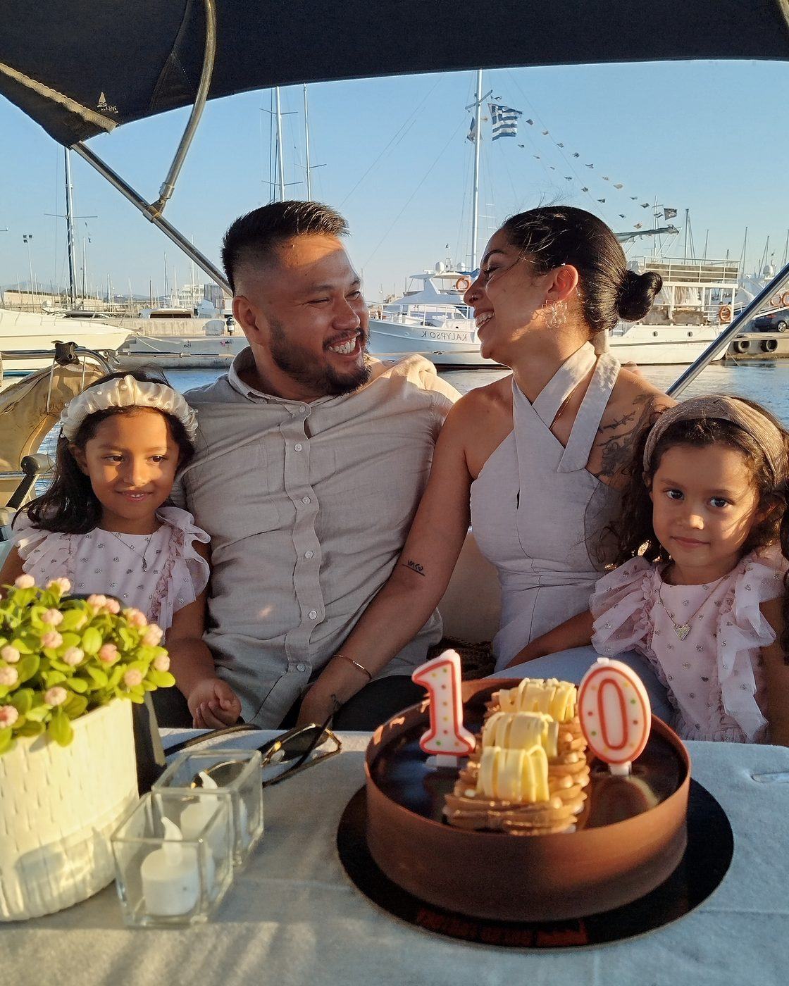 A family of four around a tenth-anniversary cake in the cockpit, the marina behind them