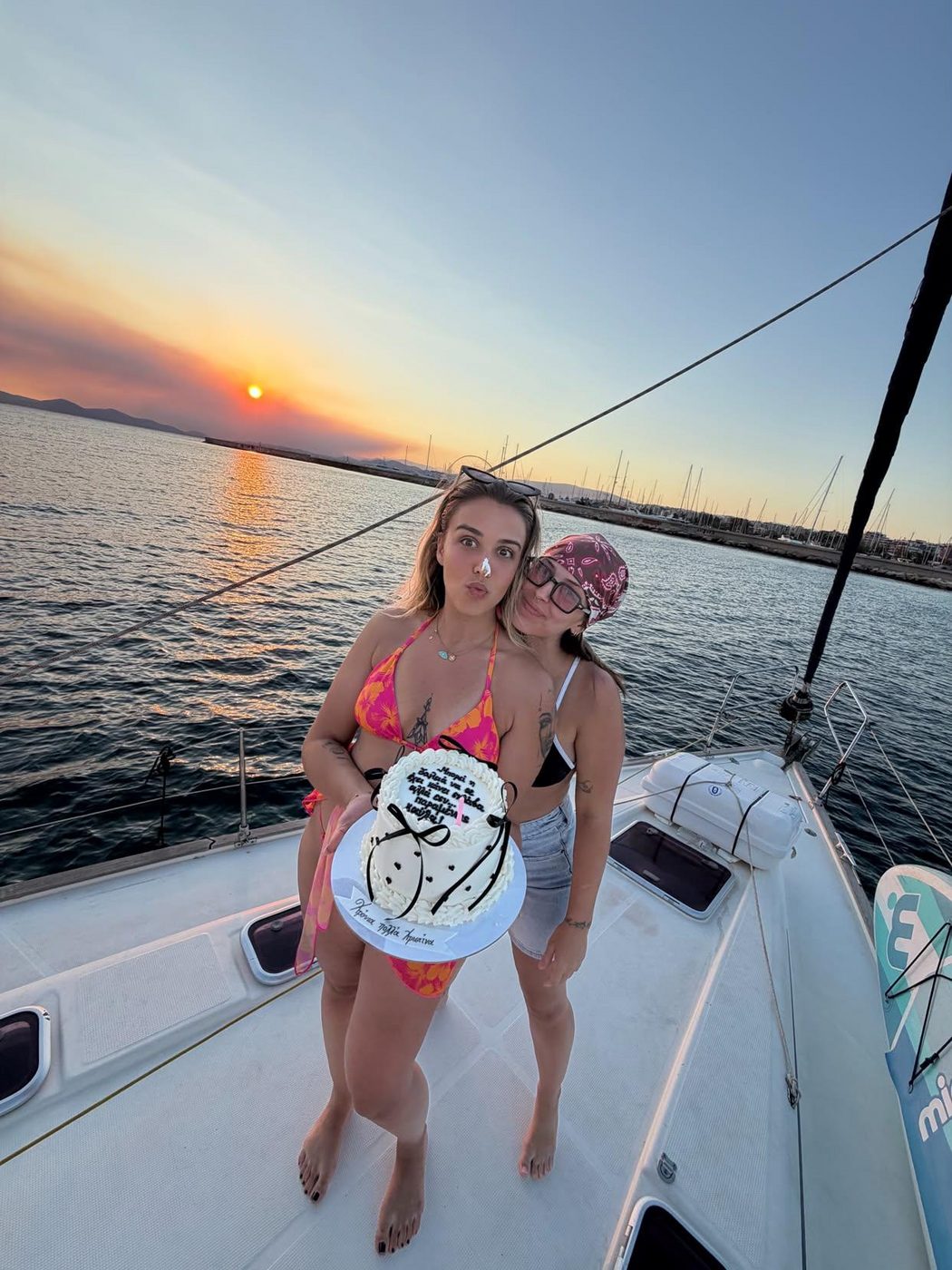A birthday cake held up on the foredeck as the sun goes down