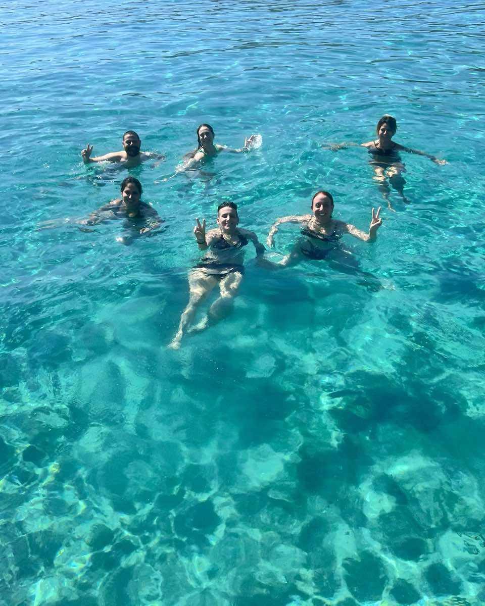 Guests swimming together in clear turquoise water beside the boat