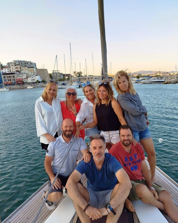 The whole group together on the foredeck as the light goes, the marina and its masts behind them